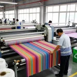 Sunwin textile manufacturing workers inspecting vibrant fabric rolls in a modern facility for quality assurance.