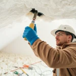 Spray foam insulation removal contractor carefully working in an attic environment.